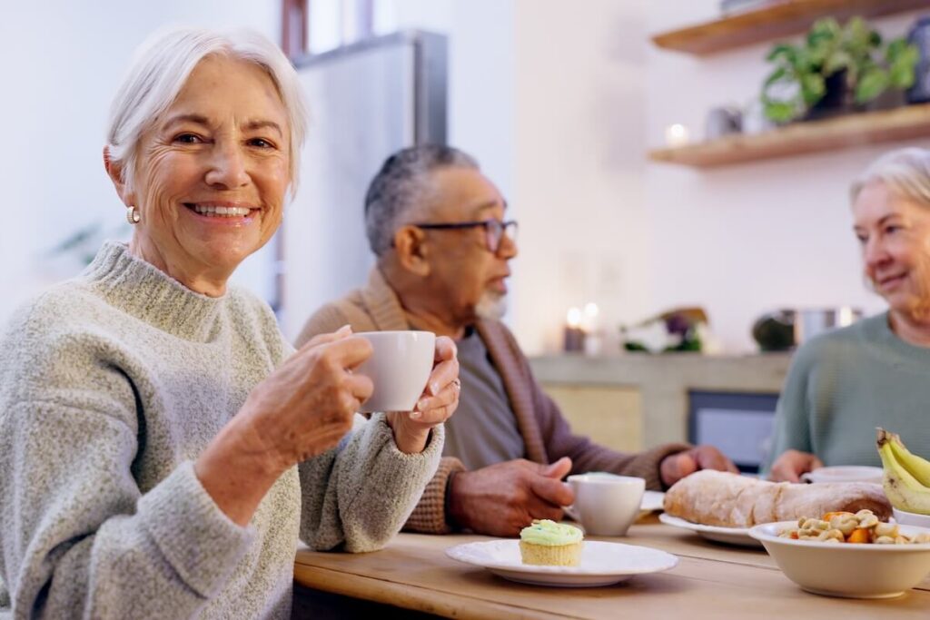 Portrait, tea party and a group of senior people in the living room of a community home for a social