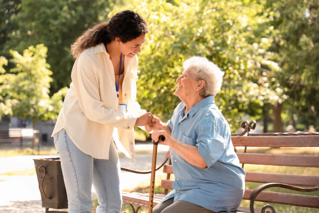 Female medical worker helping elderly woman outdoors