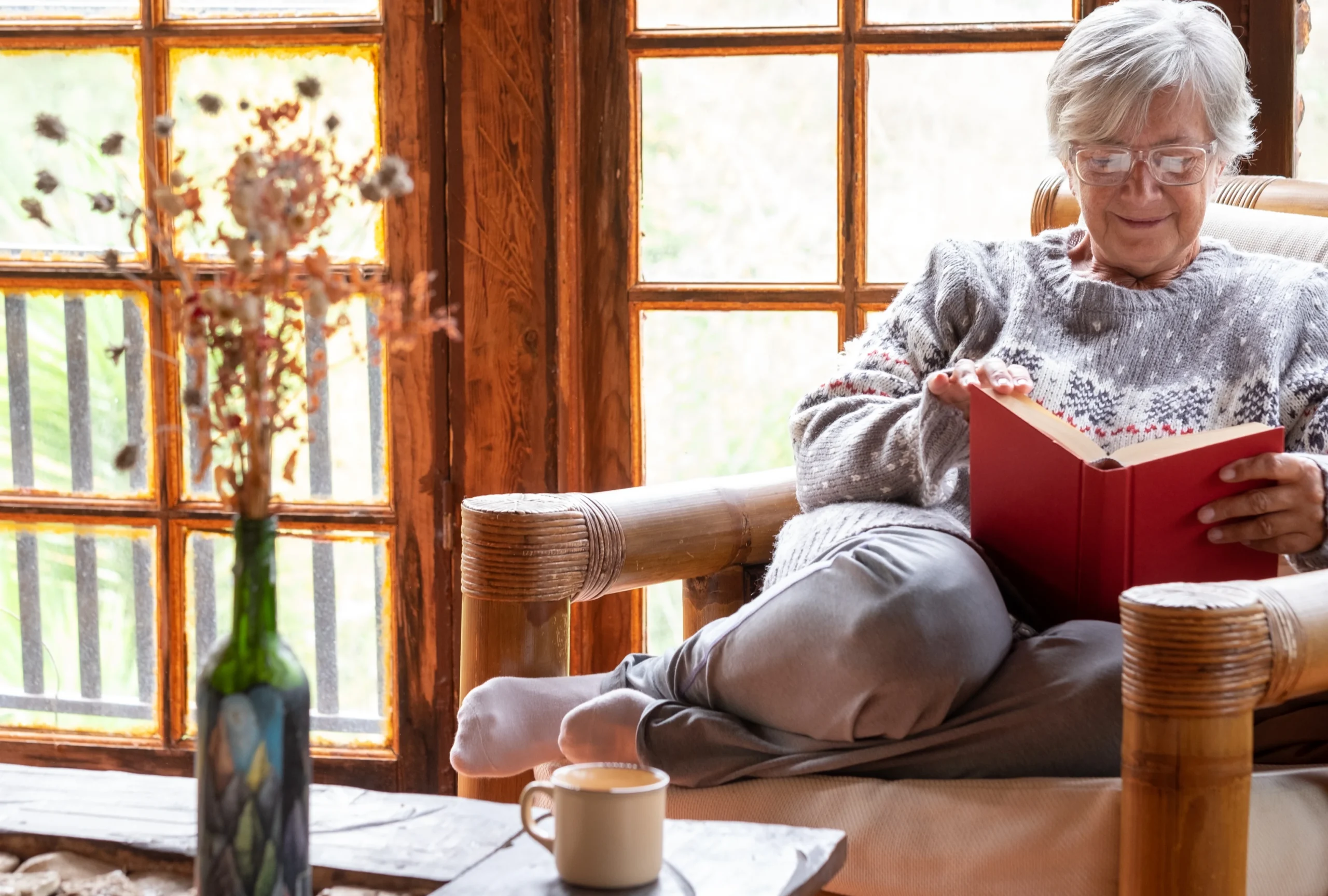 Older woman sitting comfortably in cozy armchair by window